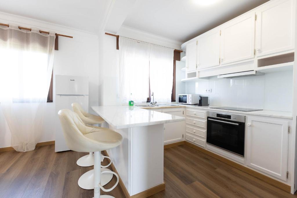 a kitchen with white cabinets and a white counter top at Trajadinha do Lima Apart in Ponte de Lima