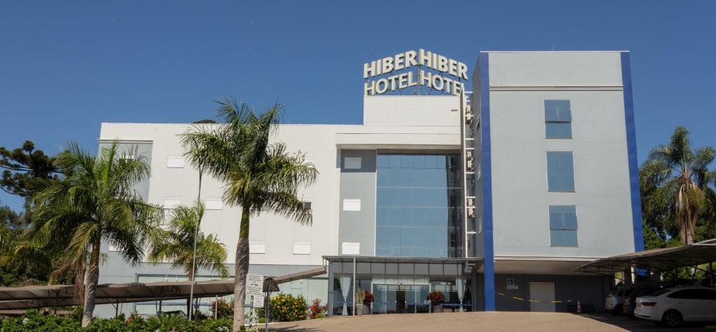 a white building with a blue sign on it at Hiber Hotel - Acesso a Chapecó in Chapecó
