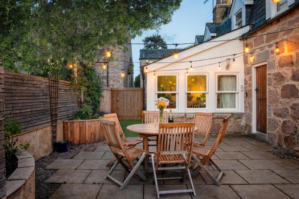 a patio with a wooden table and chairs at Riverside Cottage in Cairngorms in Ballater