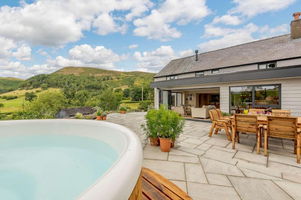 a house with a tub and a patio with a table and chairs at 4 Bed in Oswestry oc-87477 in Llansilin