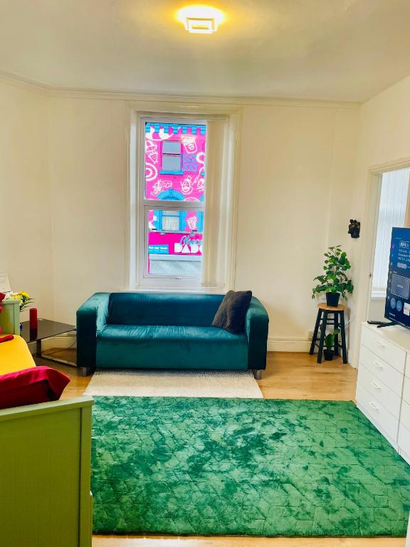 a living room with a blue couch and a window at Cozy Cottage in Liverpool