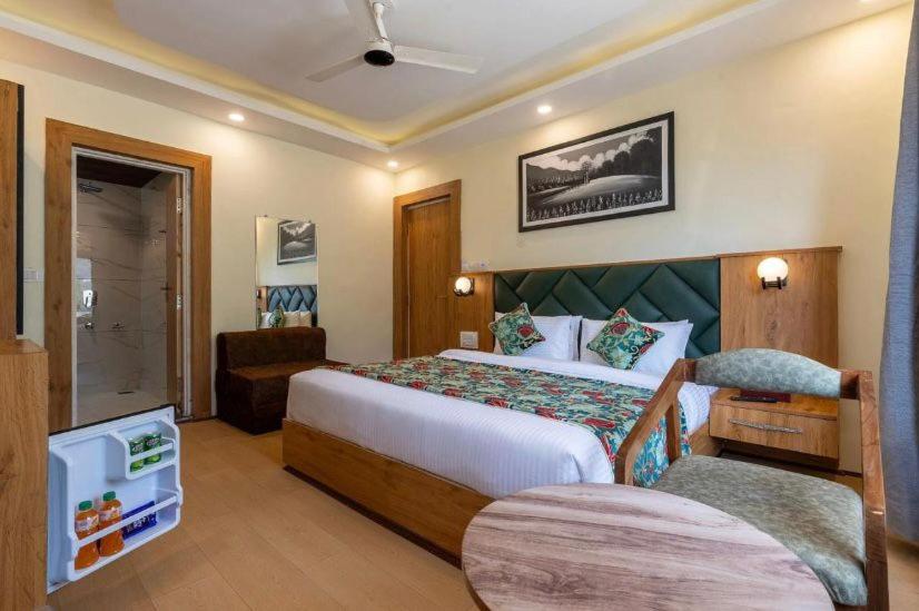 a hotel room with a large bed and a chair at Hotel Village Corner in Anantnāg