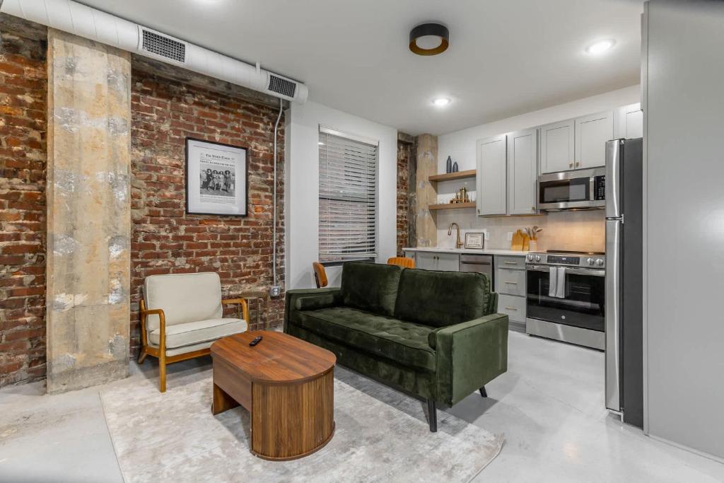 a living room with a green couch and a brick wall at Park Hotel 1BR Suite 310 in Chattanooga