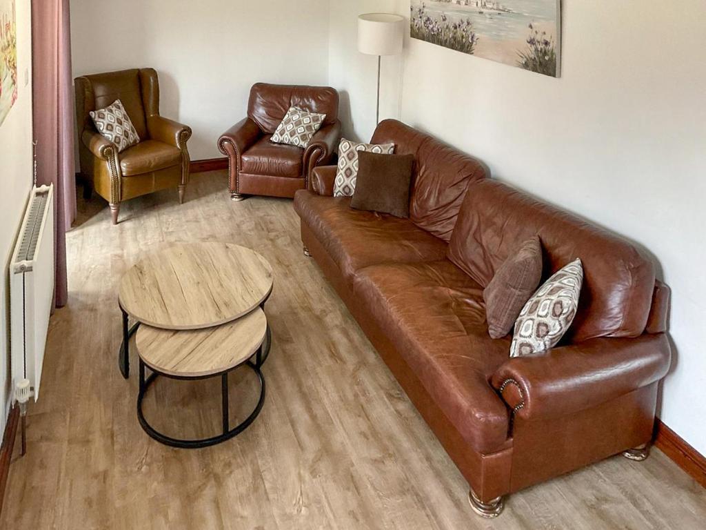 a living room with a brown leather couch and a table at Mistletoe Cottage - Uk50581 in Burnham on Sea