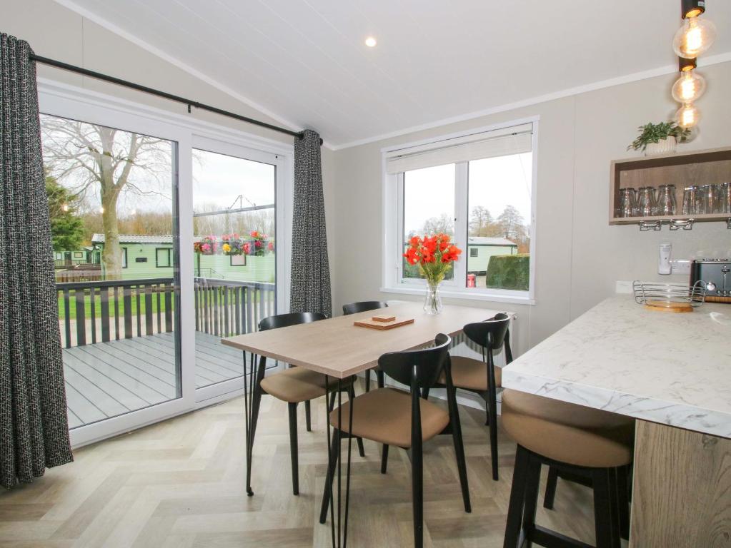 a kitchen with a table and chairs and a balcony at Poppy in Leominster