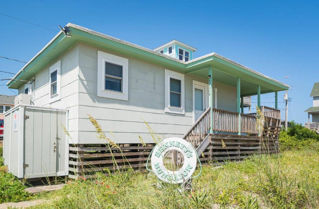 a small white house with a sign in front of it at Bennett's Bungalow - S Nags Head MP 17, 30 Yds to Beach, Year Round Flex Stays in Whalebone