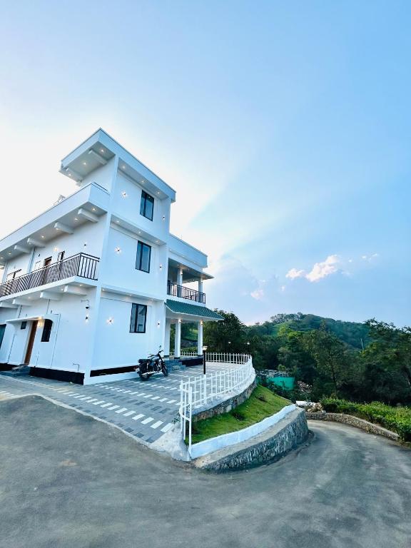 a large white building with a driveway in front of it at Flymount Homestay in Vagamon