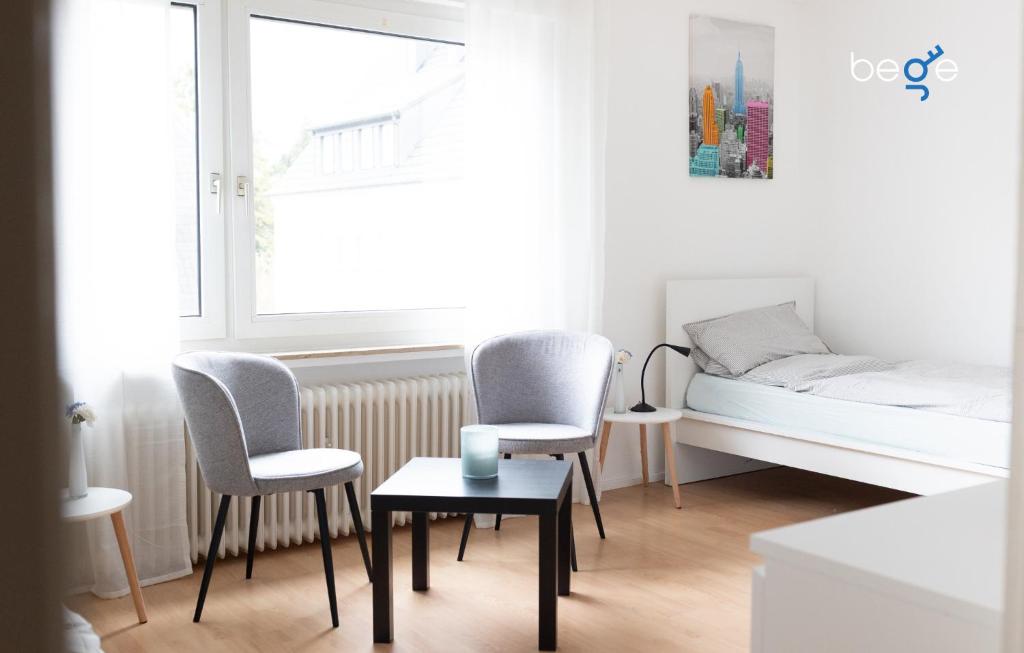 a bedroom with a bed and two chairs and a table at BEGE APARTMENTS ComfortLoft in Unna