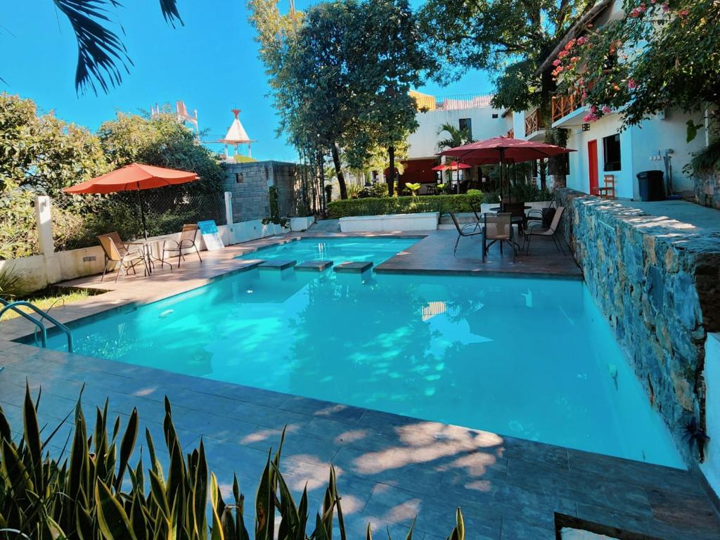 a pool with tables and chairs and umbrellas at Hotel Sierra Linda in Xilitla
