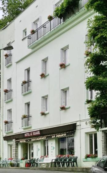 a white building with tables and chairs in front of it at Hôtel Le Square in Capvern