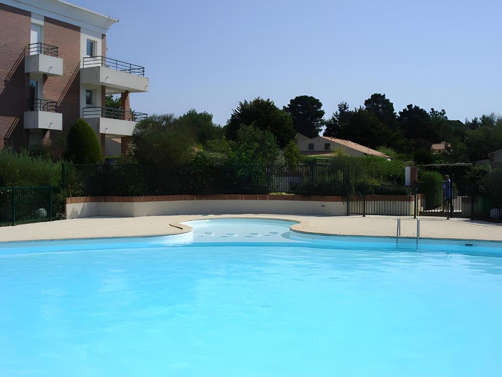 a large blue swimming pool in front of a building at Appartement du Golf - Pornic 2 in Pornic