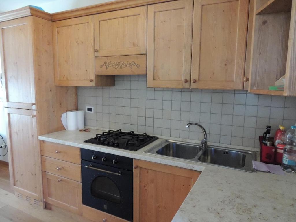 a kitchen with wooden cabinets and a stove and a sink at Ai Margini del Bosco in Sappada