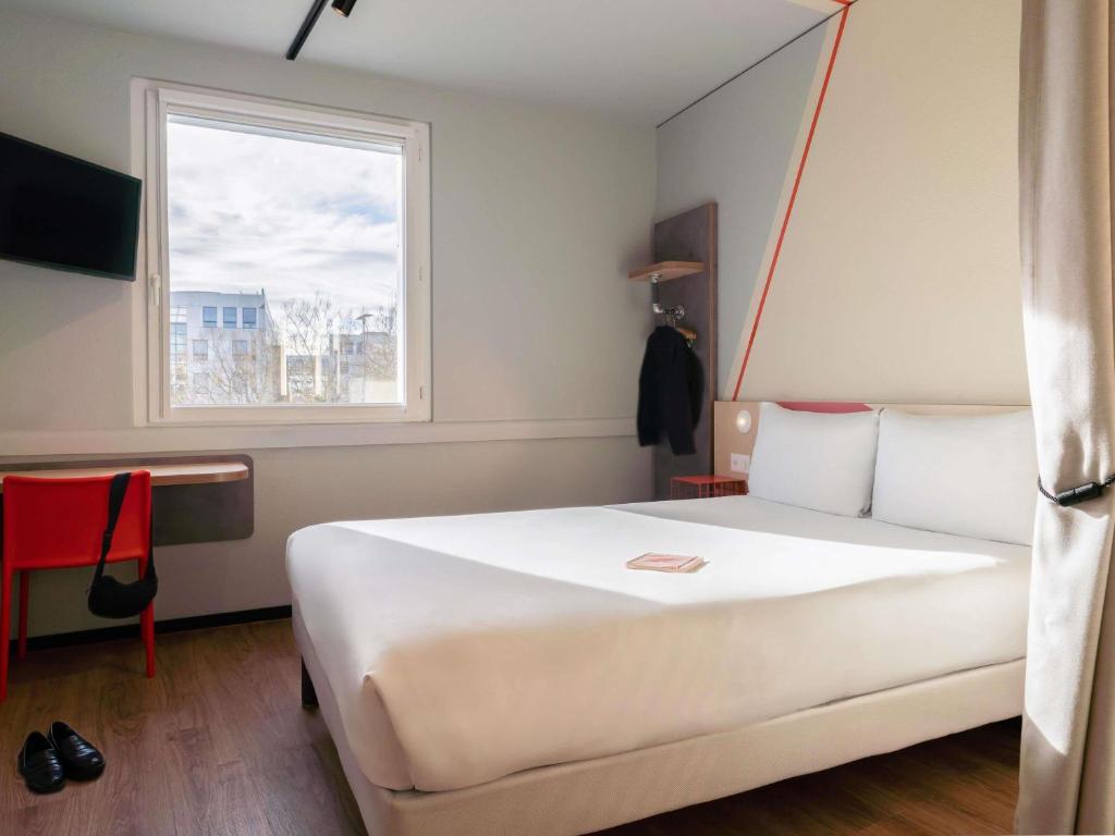a bedroom with a large white bed with a window at ibis budget Genève Petit-Lancy in Geneva