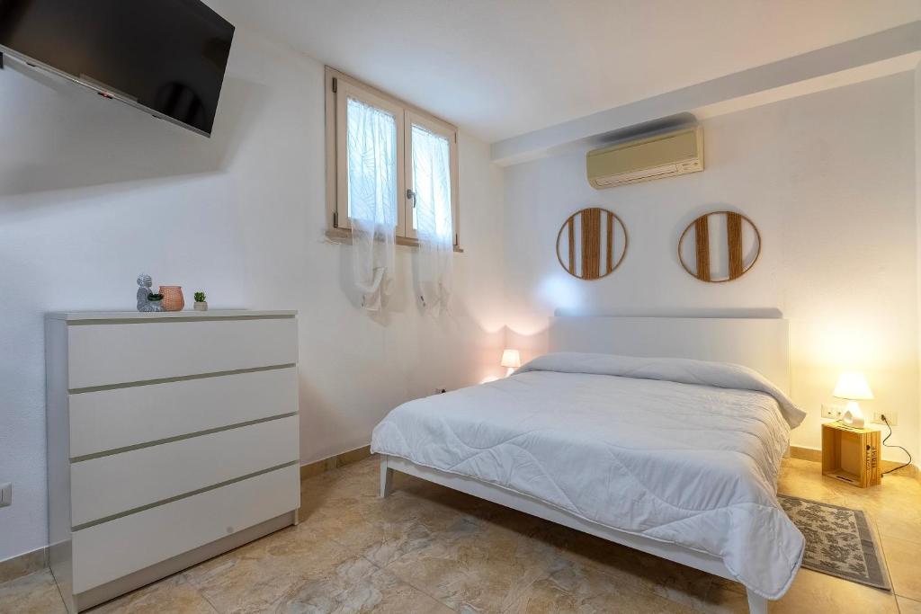 a white bedroom with a bed and two mirrors at L'Angolo Monolocale- Porto Torres in Porto Torres
