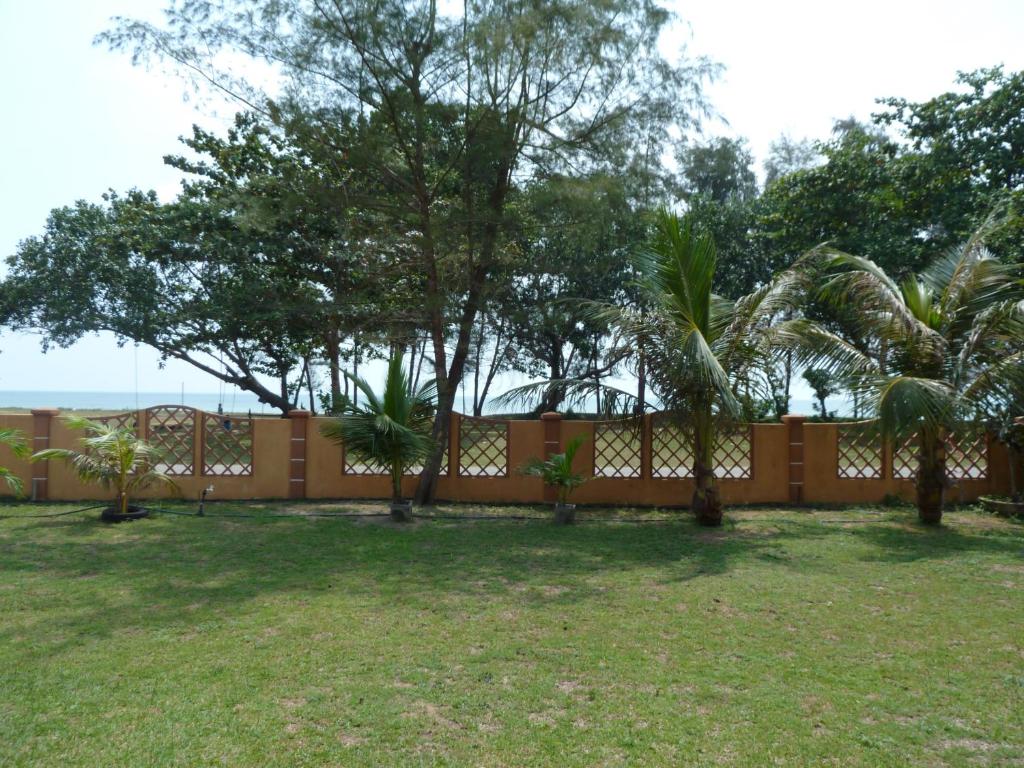 a fence with palm trees in front of a yard at Cempaka Beach Resort in Kuantan