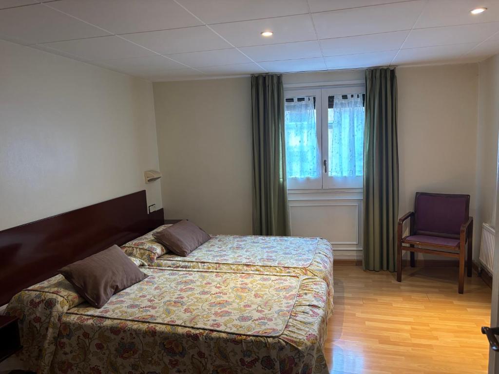 a hotel room with two beds and a chair at Hostal Ripollès in Ripoll