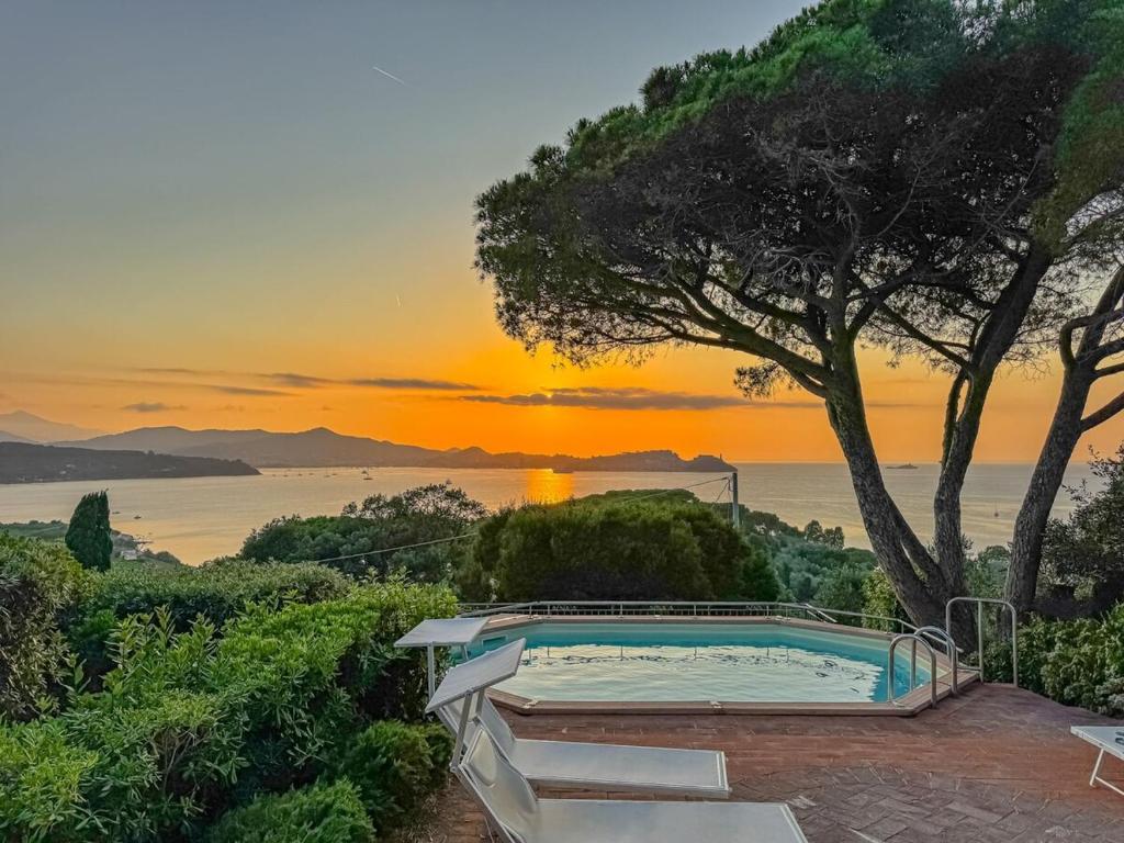 a swimming pool with a sunset in the background at Villa Les Ombrelles in Portoferraio