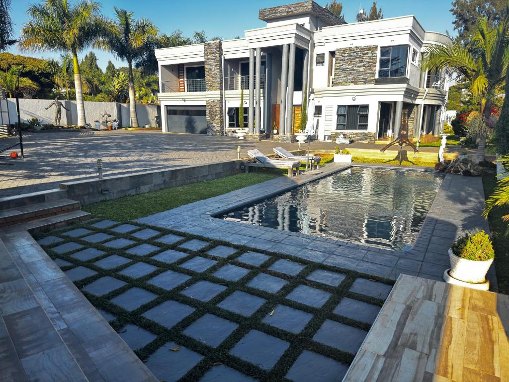 a house with a swimming pool in front of a house at Falcon Guest House in Harare
