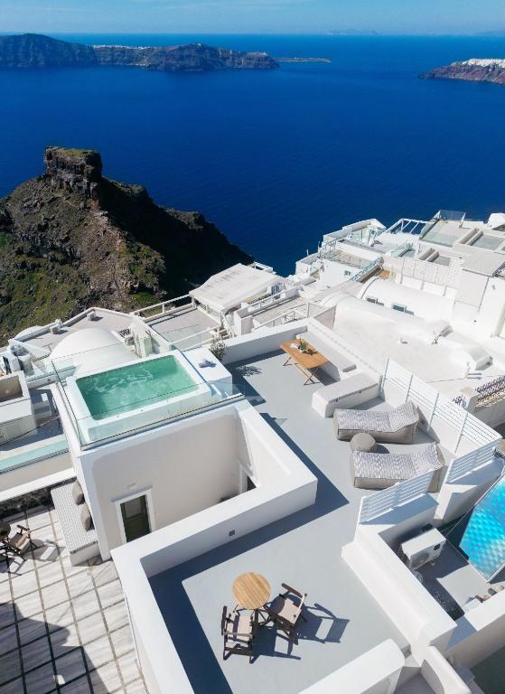 a view of a white building with chairs and the ocean at Ocean Caldera View Villa by Dalmyra Estate in Imerovigli