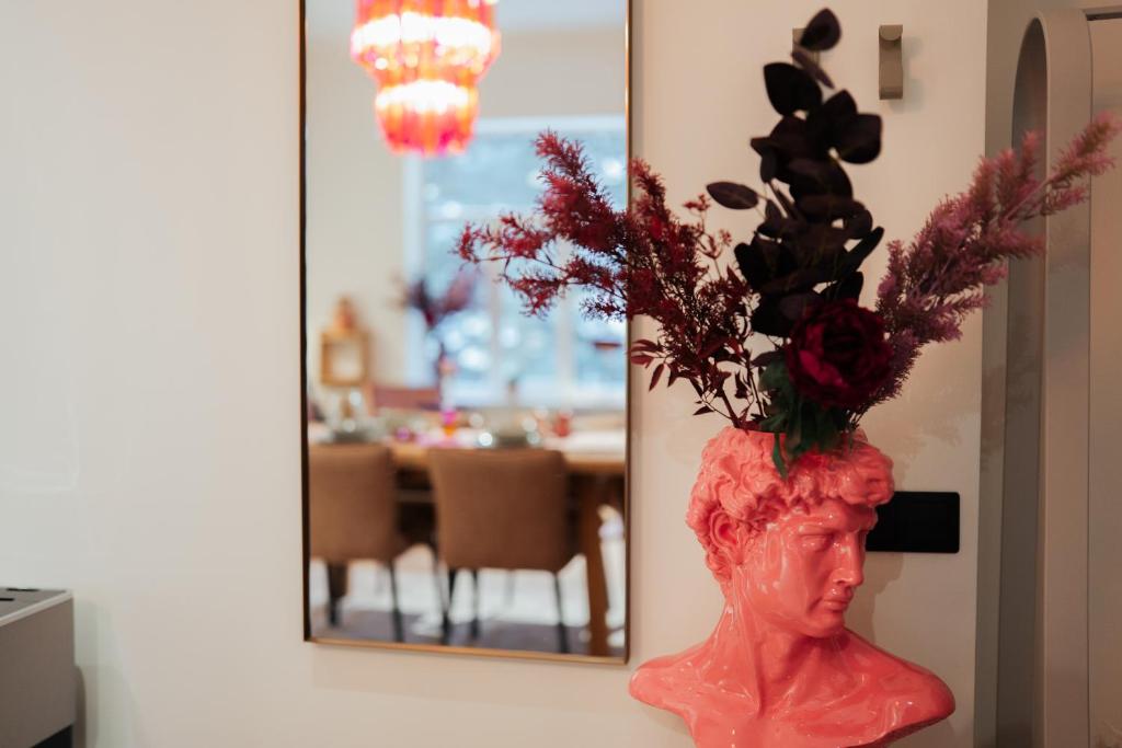a vase with flowers in front of a mirror at Rozā Dāvids in Liepāja
