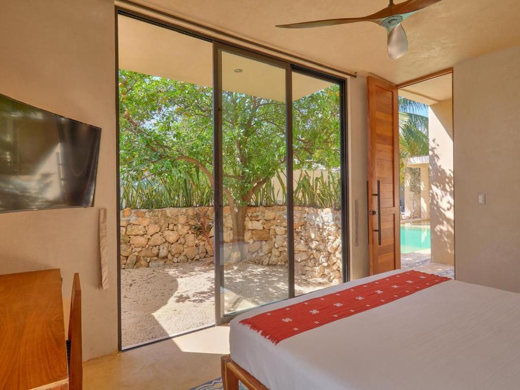 a bedroom with a bed and a large glass window at suite tropical en oasis tropical del centro de Mérida in Mérida