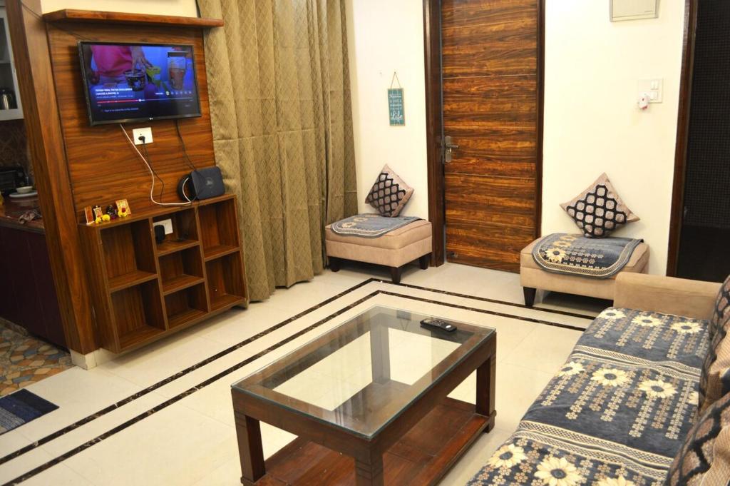 a living room with a coffee table and a tv at Ananta 1BHK in Birbhaddar