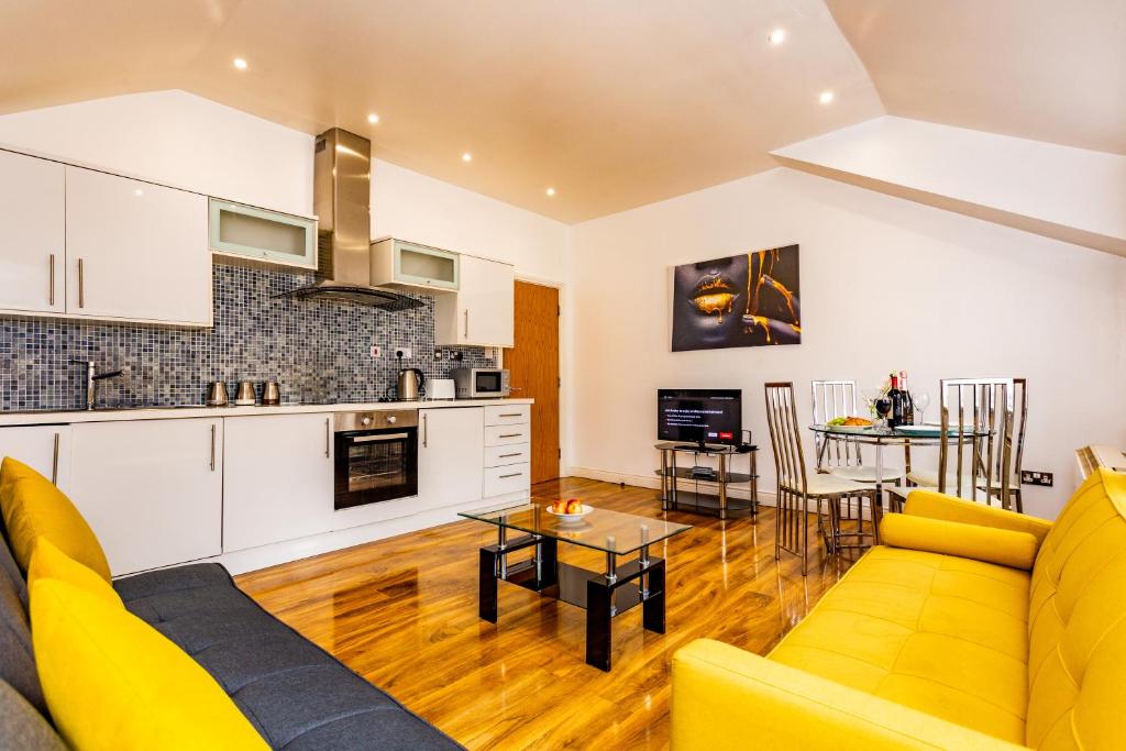 a living room with a yellow couch and a kitchen at Exclusive Apartment in Newcastle upon Tyne