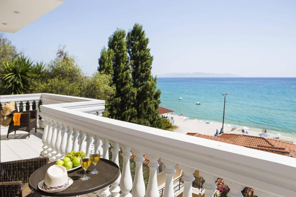 a balcony with a table with a bowl of fruit and the ocean at Villa Lourdas Beach by Villa Plus in Trápeza