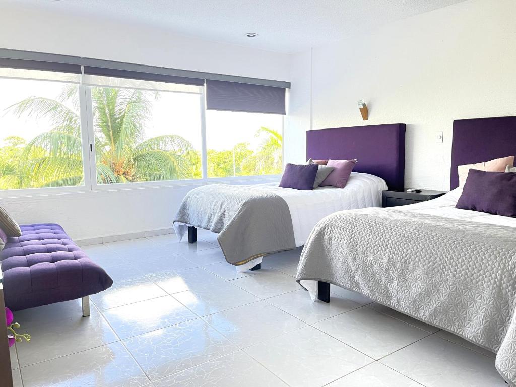 a bedroom with two beds and a purple chair at Divine Suite Cancun - BEACH CONDO - 6PX in Cancún