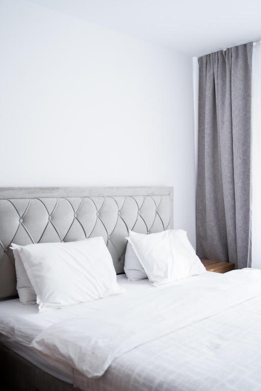 a bed with white sheets and pillows in a bedroom at Apartament centru in Râmnicu Vâlcea
