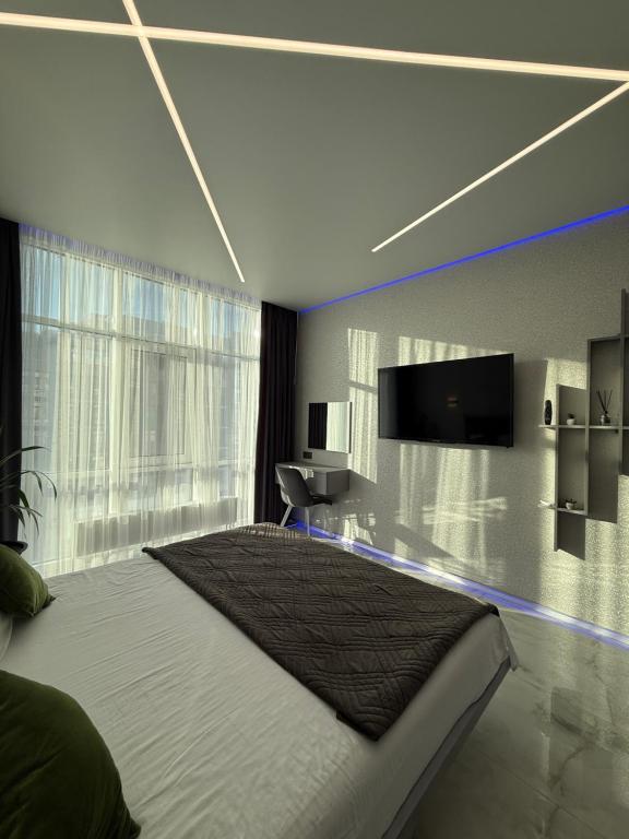 a bedroom with a large bed and a tv on the wall at ЖК Елегія парк in Odesa