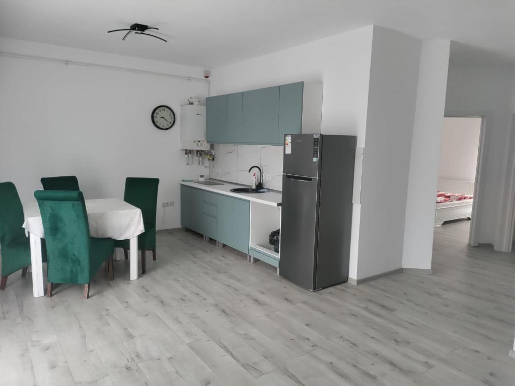a kitchen with a refrigerator and a table and chairs at Park & Rest Apartment in Mărtineşti