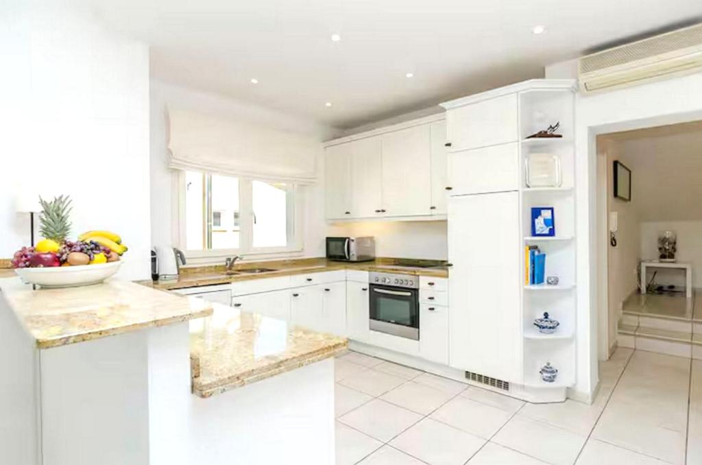 a kitchen with white cabinets and a bowl of fruit on the counter at Casa CedenoXavi in Santa Ponsa