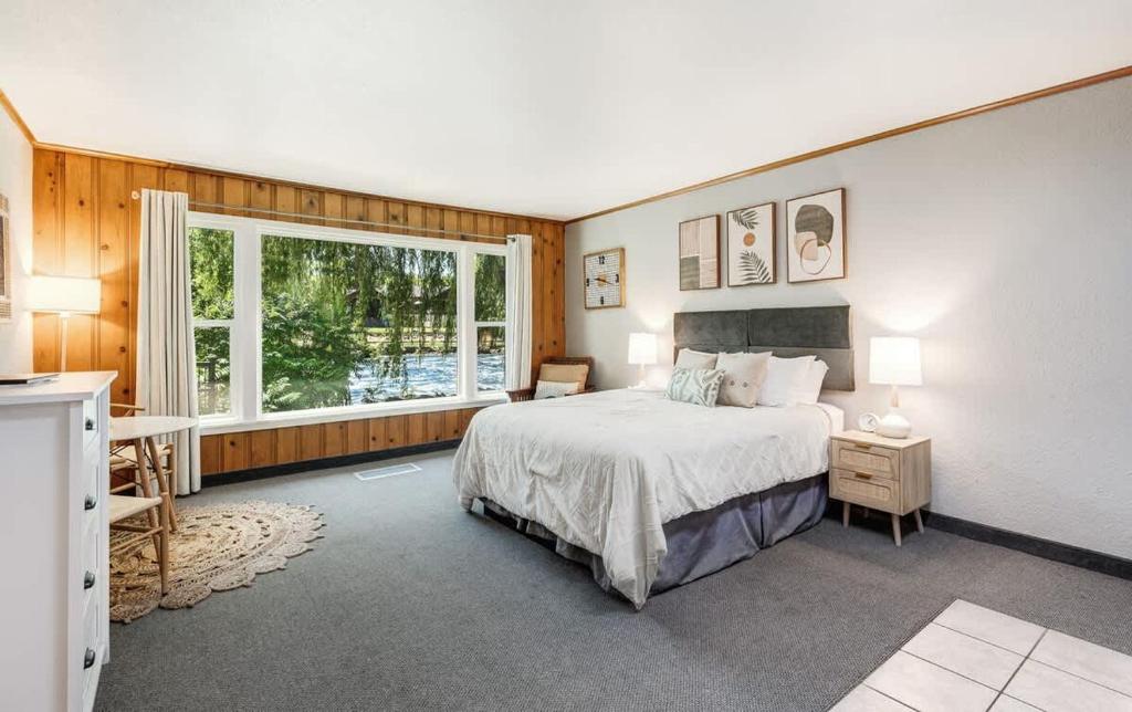 a bedroom with a bed and a large window at Ground Floor River Front Studio Cottage in Bend