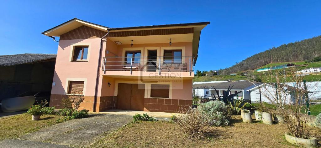 a pink house with a balcony on a hill at Villa Trinamar - Casa rural en Valdes cerca de Luarca in Carcedo