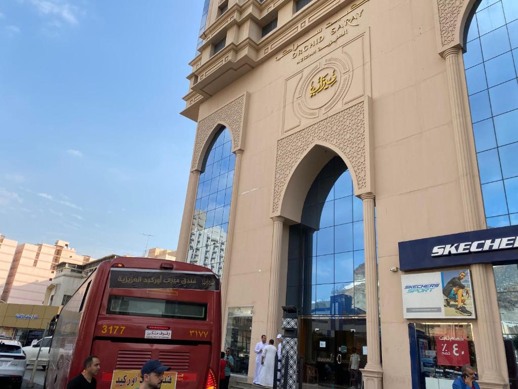 a red double decker bus parked in front of a building at فندق العزيزية توصيل للحرم in Mecca