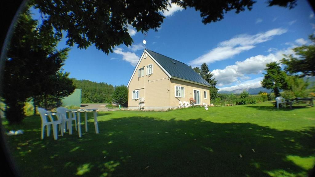 a house with a table and chairs in a yard at Hillview cottage Sanfurano in Kami-furano