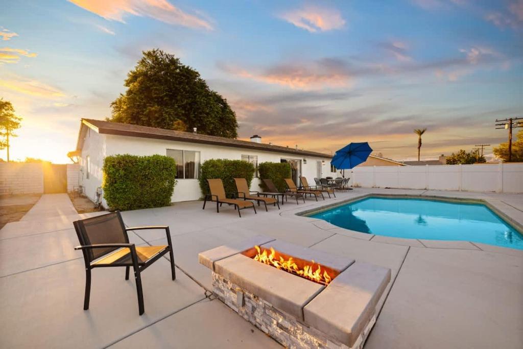 a patio with a fireplace next to a swimming pool at Cozy Retreat with Pool, BBQ and Fire Pit in Indio