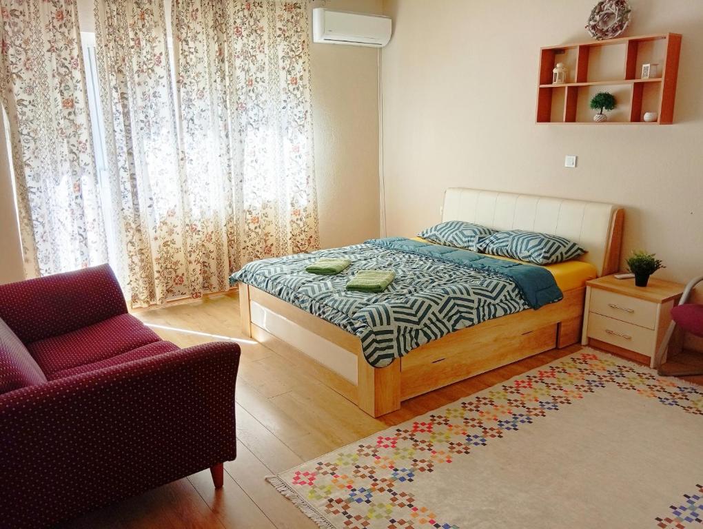 a bedroom with a bed and a chair and a rug at Harmony Apartment in Strumica