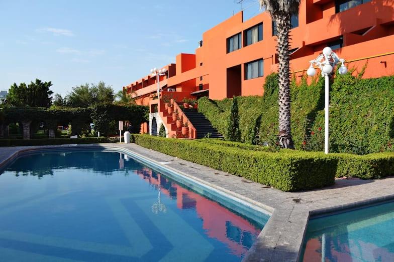 a swimming pool in front of a building at Hotel Vilamiño in Aguascalientes