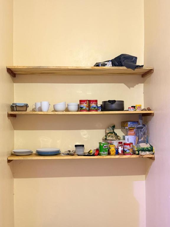 a shelf with bowls and other food items on it at Ways Rest in Msaranga