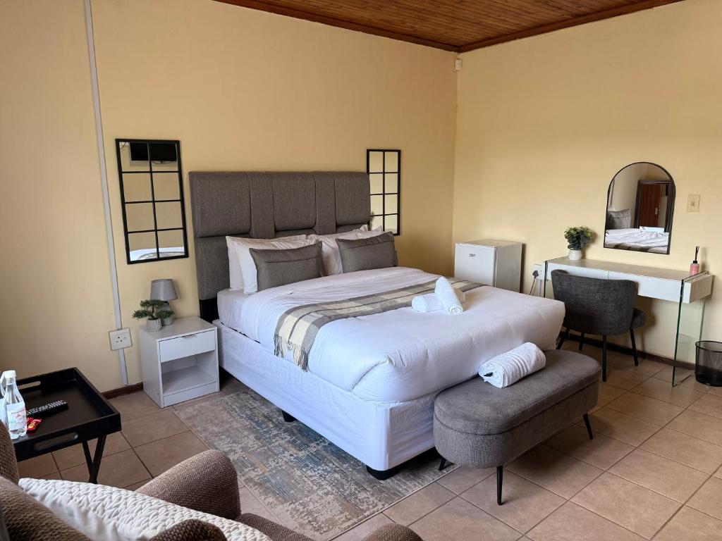 a bedroom with a large white bed and a chair at Soulfenda guest house in Graskop