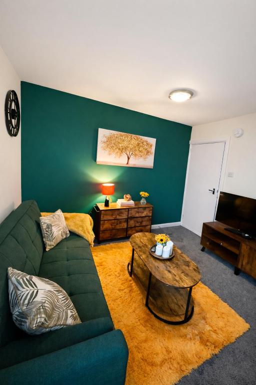 a living room with a green couch and a table at Harbour Lights Retreat-Small and Cosy 1 bedroom in Ferryden
