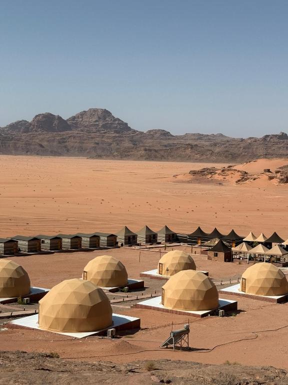 a group of tents in a desert with mountains in the background at Mangle luxury rum camp in Disah