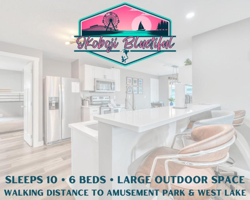 a kitchen with a large white counter and chairs at Okoboji BLUEtiful Cottage in Arnolds Park