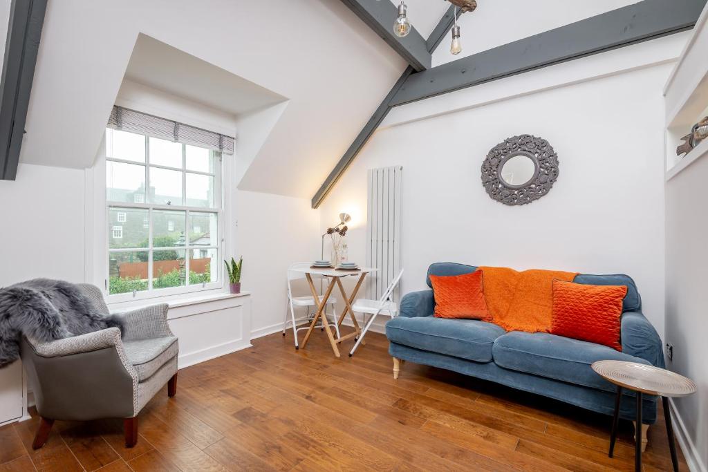 a living room with a blue couch and a chair at WeeLoft - St Andrews Studio Apartment in St. Andrews