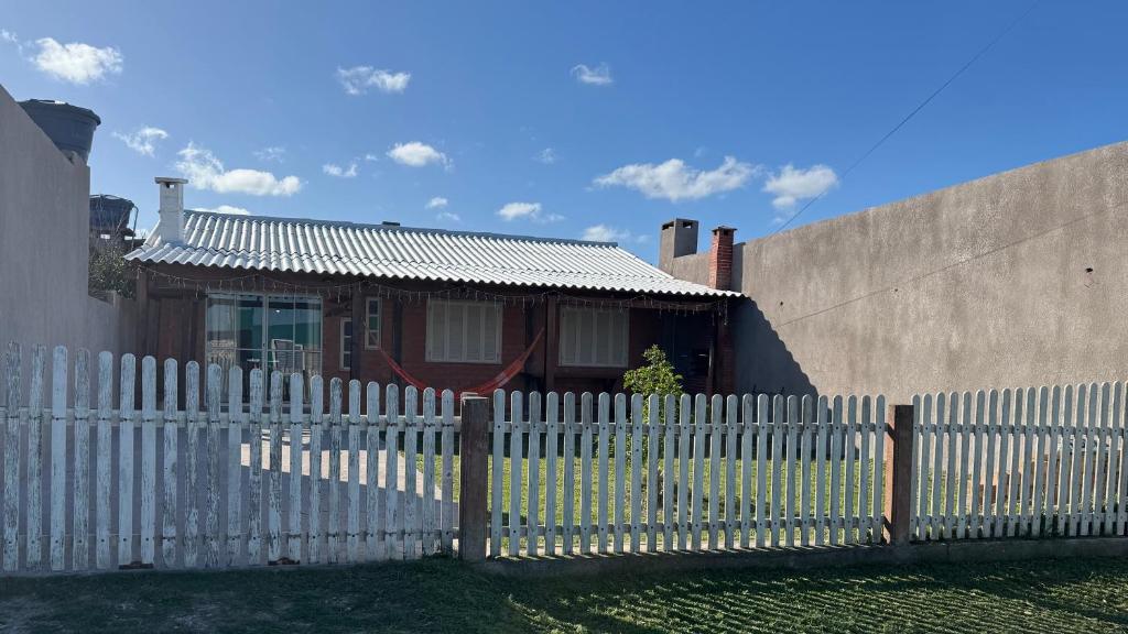 a white picket fence in front of a house at House on Hermenegildo Beach in Santa Vitória do Palmar