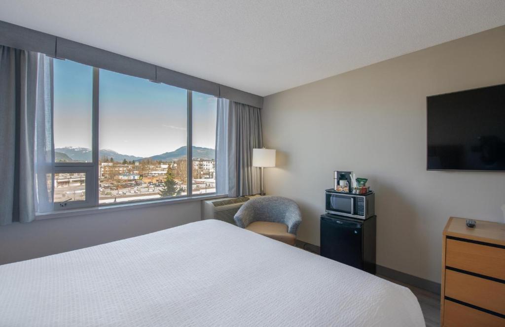 a hotel room with a bed and a large window at Coast Chilliwack Hotel by APA in Chilliwack