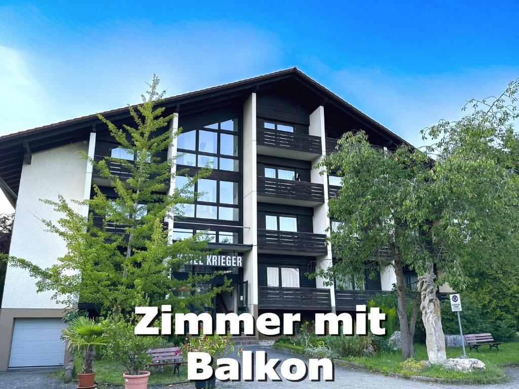 un edificio con un albero di fronte di Hotel Krieger Regensburg a Pettendorf