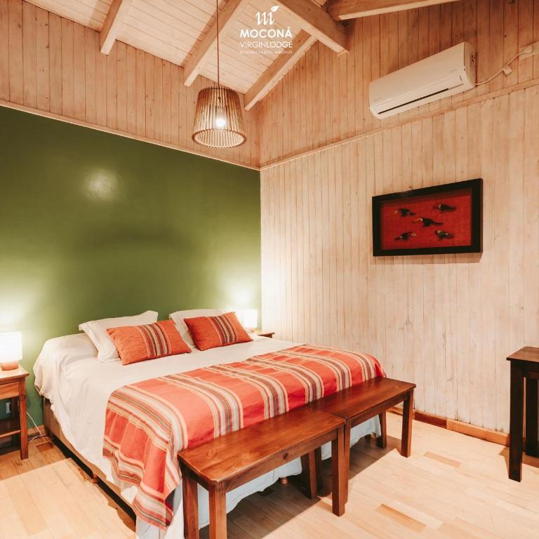 a bedroom with a bed and a bench in it at Moconá Virgin Lodge in Moconá Falls